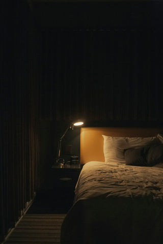 A bedroom lit with soft, warm layered lighting rather than one bright ceiling light
