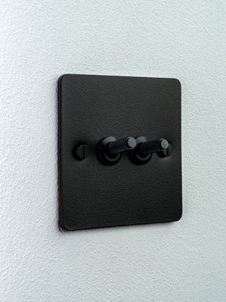 Black double toggle light switch on a white wall