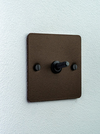 Warm-toned toggle light switch on a white wall