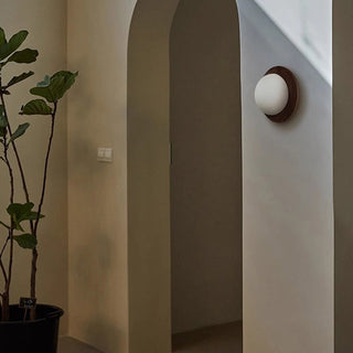 Natural wood round minimalist wall lamp illuminated — sconce