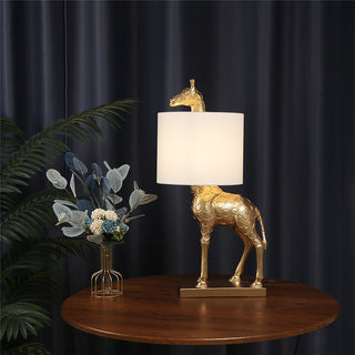 Gold giraffe table lamp illuminated — designer warm glow
