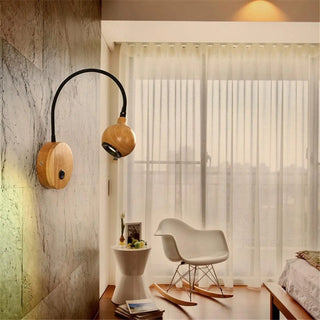 Black wood reading wall sconce installed above bed warm glow