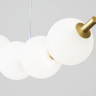Modern white acrylic ball chandelier detail — brass pendant warm