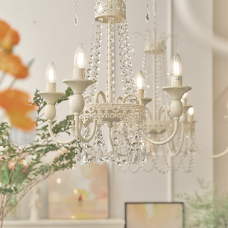 Vintage white chandelier illuminated — crystal tassel glass warm luxury